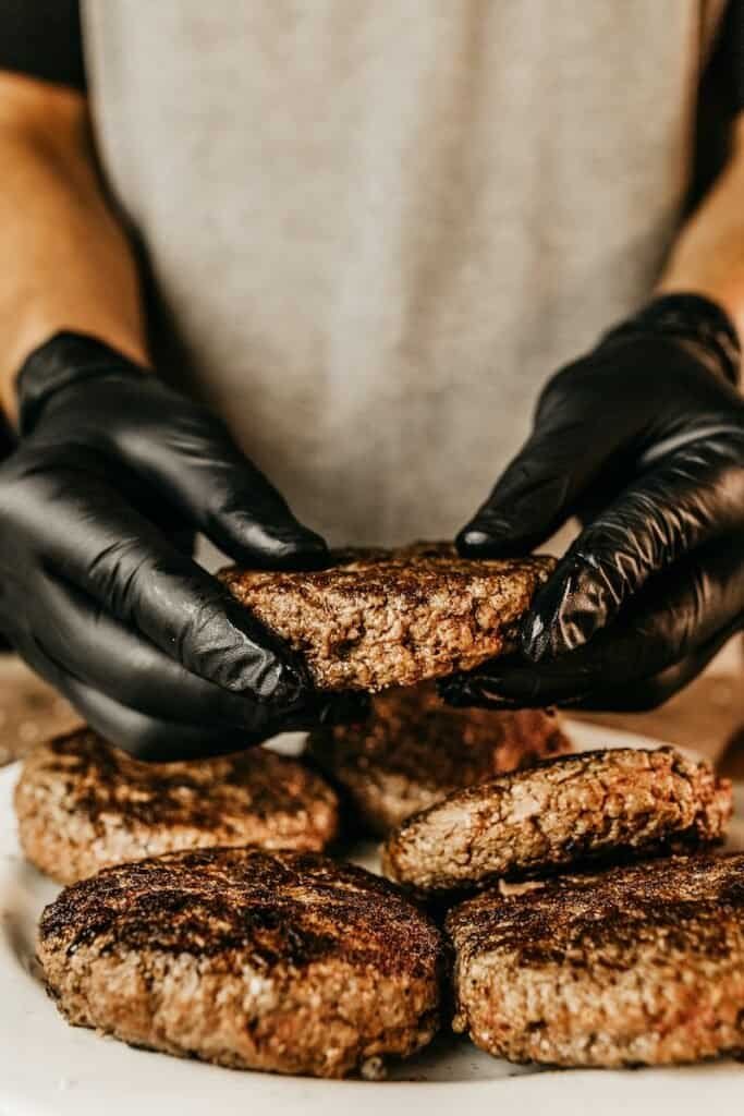 que tipo de carne tiene una hamburguesa - person in black leather gloves holding brown bread