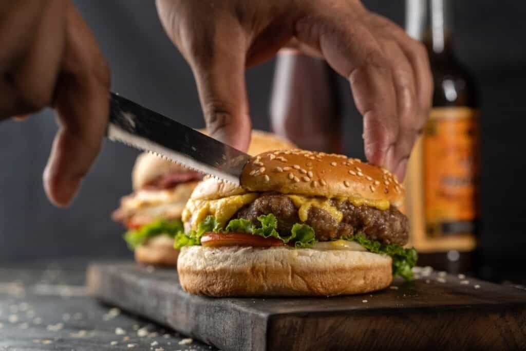 como corto hamburguesas sin que todo se desmorone - person holding burger with lettuce and tomato