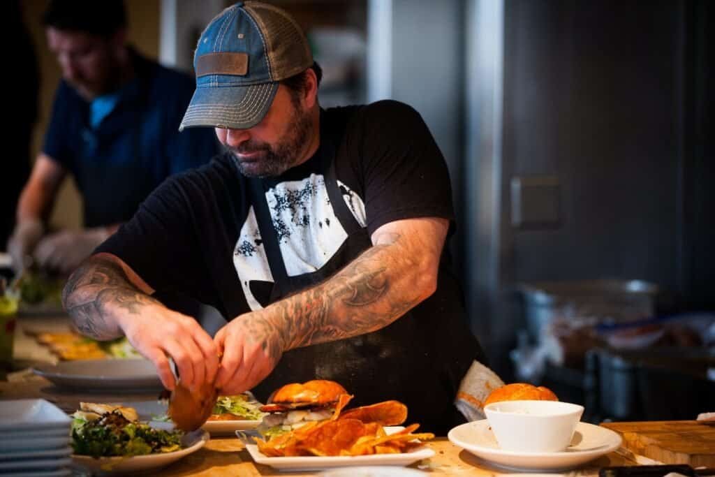 como montar una hamburgueseria paso a paso - man standing beside table while holding food